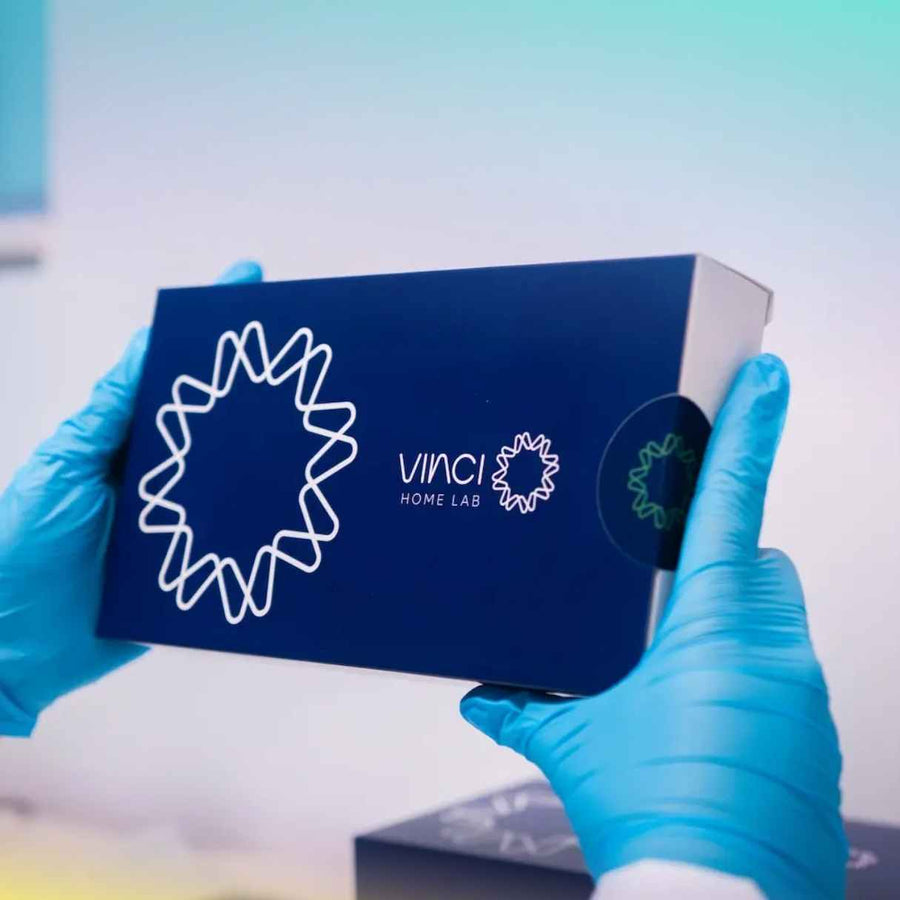 Mãos segurando o kit de autocoleta da Vinci Lab com luvas azuis